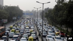 In this Jan. 16, 2016, file photo, vehicles move slowly through a traffic intersection after the end of a two-week experiment to reduce the number of cars to fight pollution in in New Delhi, India. (AP Photo/Altaf Qadri, File)