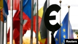 A statue depicting European unity is seen near EU flags outside the European Parliament in Brussels, Belgium, Oct.12, 2012.