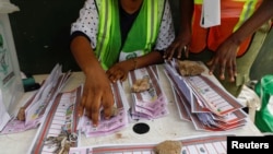 FILE - Electoral officials use stones to hold down ballots during the vote counting process of the gubernatorial election at a polling unit in Lagos, Nigeria March 18, 2023. 