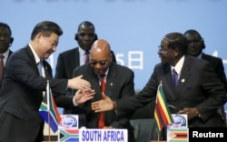 FILE - China’s president, Xi Jinping, left, shakes hands with the former president of Zimbabwe, Robert Mugabe, right, while South Africa’s former President Jacob Zuma looks on during a Forum on China-Africa Cooperation in Sandton, Johannesburg, Dec. 4, 2015.