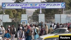 Afganos se encuentran frente a la puerta principal del Aeropuerto Internacional Hamid Karzai en Kabul, el 31 de agosto de 2021, un día después del retiro total de las tropas de EE. UU. tras 20 años de conflicto.