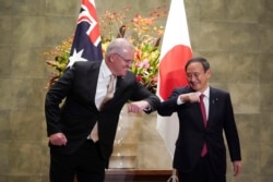 FILE - Australian Prime Minister Scott Morrison, left, and Japanese Prime Minister Yoshihide Suga bump elbows to greet prior to the official welcome ceremony at Suga's official residence in Tokyo Tuesday, Nov. 17, 2020.
