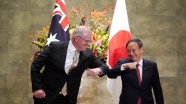 FILE - Australian Prime Minister Scott Morrison, left, and Japanese Prime Minister Yoshihide Suga bump elbows to greet prior to the official welcome ceremony at Suga's official residence in Tokyo Tuesday, Nov. 17, 2020.