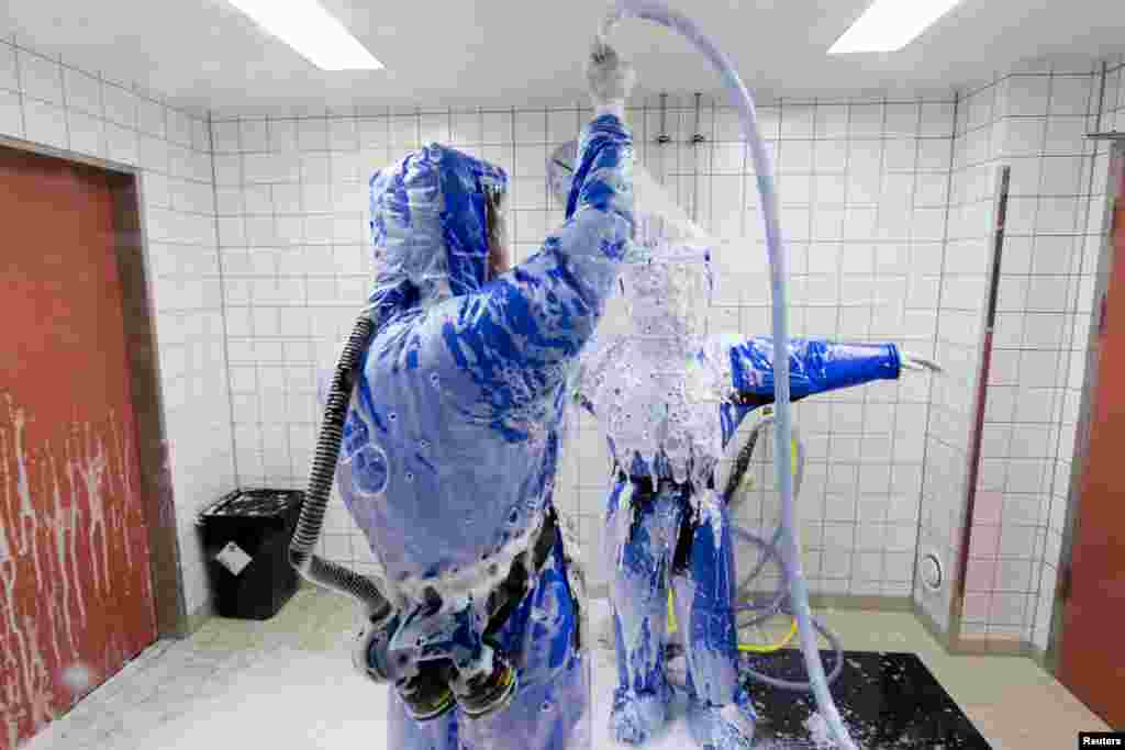 Docteur en médecine tropicale, Florian Steiner (G) nettoie la salle du médecin Thomas Klotzkowski dans une chambre de désinfection à la station de quarantaine pour les patients atteints de maladies infectieuses à l&#39;hôpital de la Charité à Berlin, le 11 Août 2014. REUTERS / Thomas 