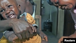 Aliyatu Abdulai (R), a Sierra Leonean Maternal and Child Health Aide, administers a vaccine to a child in the village of Sembehun, outside the town of Bo, in the southeast region of the West African country, which is supported by the GAVI Alliance that fu