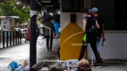 Dalam foto yang diambil pada 17 Juli 2020 ini tampak seorang wanita menatap seorang tuna wisma yang tengah tertidur di area jalan Hamra di kota Beirut, Lebanon. (Foto: AP)