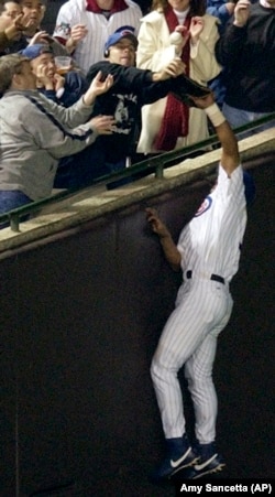 Chicago Cubs left fielder Moises Alou reaches into the stands unsuccessfully for a foul ball against the Florida Marlins in the eighth inning during Game 6 of the National League championship series