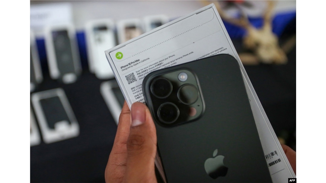 Seorang pejabat bea cukai Indonesia menunjukkan iPhone 16 Pro Max yang diselundupkan sebelum menghancurkannya setelah disita bersama puluhan ponsel dan tablet Apple, di kantor bea cukai Bandara Internasional Soekarno-Hatta di Tangerang, Banten, pada 29 November 2024. (AFP)