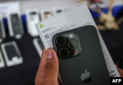 Seorang pejabat bea cukai Indonesia menunjukkan iPhone 16 Pro Max yang diselundupkan sebelum menghancurkannya setelah disita bersama puluhan ponsel dan tablet Apple, di kantor bea cukai Bandara Internasional Soekarno-Hatta di Tangerang, Banten, pada 29 November 2024. (AFP)