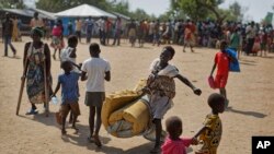 FILE - A South Sudanese refugee girl with a baby on her back carries a foam mattress, June 9, 2017, to the communal tent at the Imvepi reception center, where newly arrived refugees are processed before being allocated plots of land in nearby Bidi Bidi refugee camp.