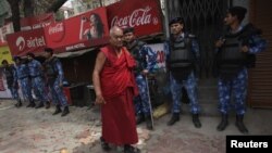 Tibetan exile walks past Rapid Action Force personnel at Majnu Ka Tila, a Tibetan refugee camp, New Delhi, March 27, 2012.