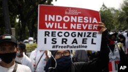 A woman holds up a poster during a rally against Israel's attacks on Gaza, outside the U.S. Embassy in Jakarta, Indonesia, May 21, 2021. 