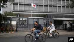 资料照：骑车人从日本驻北京大使馆前驶过。