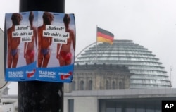 FILE - An election poster of the nationalist Alternative for Germany, AfD, reading "Burka? We prefer bikinis" hangs on a lamp post in front of the Parliament building Berlin, Germany, Sept. 24, 2017. Some Germans fear that a new election would only strengthen the hand of the far-right.
