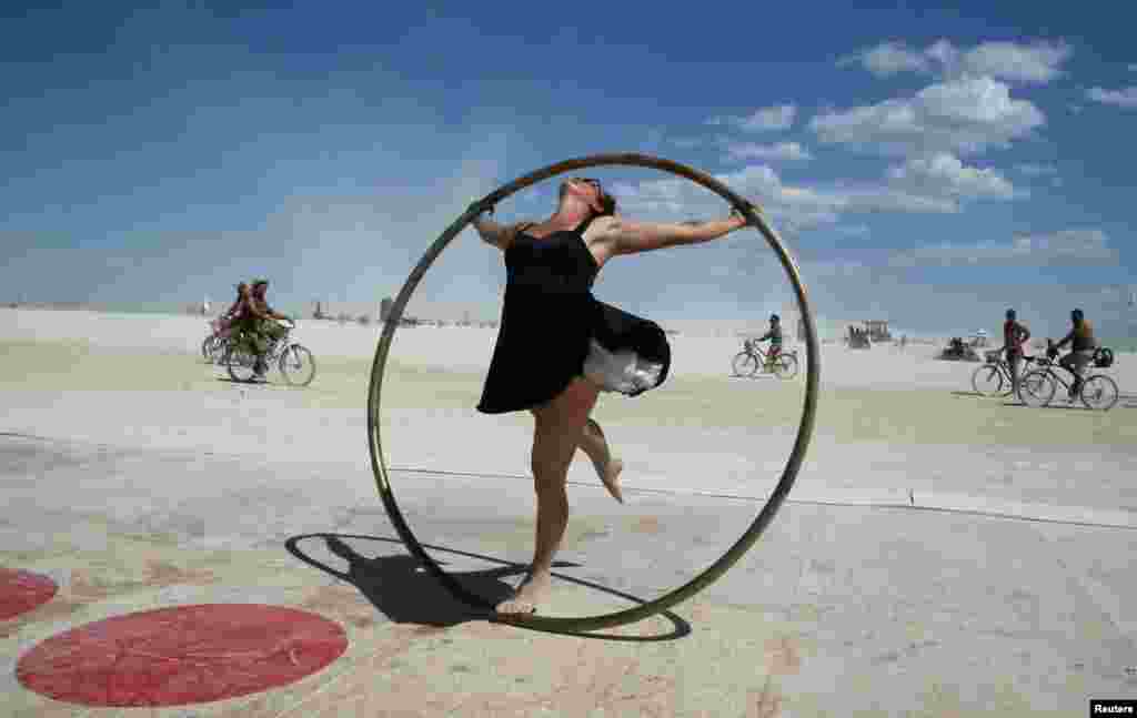 Burning Man participant Kylie Webb spins inside a metal hoop on a roller disco floor as approximately 70,000 people from all over the world gathered for the 1st full day of the annual Burning Man arts and music festival in the middle of the Black Rock Des