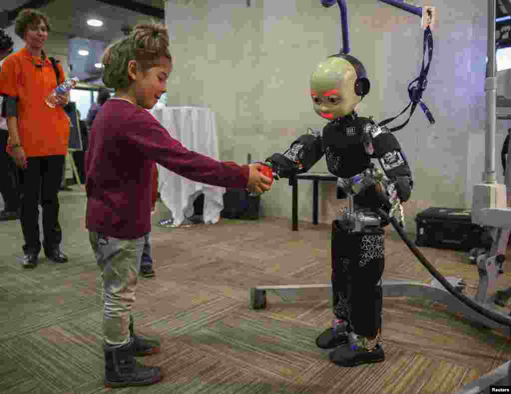 A girl gives a ball to a humanoid robot during the International Conference on Humanoid Robots in Madrid, Spain.