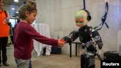 Una niña entrega una pelota a un robot humanizado en una conferencia en Madrid.