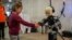 Una niña entrega una pelota a un robot humanizado en una conferencia en Madrid.