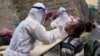 在中国新疆乌鲁木齐一名穿着防护服的医务工作者对居民进行核酸检测。（2020年7月19日）