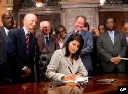 FILE - Then-South Carolina Gov. Nikki Haley signs a bill into law as former South Carolina governors and officials look on, July 9, 2015, at the Statehouse in Columbia, S.C. The law enabled the removal of the Confederate flag from the Statehouse grounds more than 50 years after the rebel banner was raised to protest the civil rights movement.