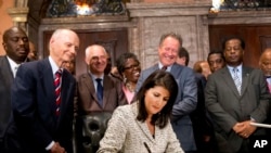 South Carolina Gov. Nikki Haley signs a bill into law as former South Carolina governors and officials look on Thursday, July 9, 2015.