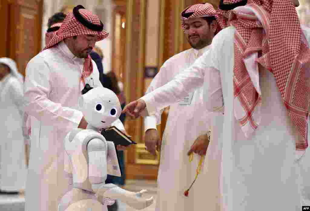 Representatives talk near a robot during the Future Investment Initiative forum at the King Abdulaziz Conference Center in Saudi Arabia&#39;s capital Riyadh.