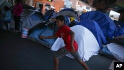 A youth plays in a makeshift migrant camp near El Chaparral pedestrian border bridge in Tijuana, Mexico, July 1, 2021. 