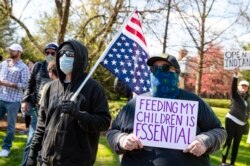 Protesters gather outside the Indiana governor's mansion in Indianapolis, Saturday, April 18, 2020, to protest against the governor's stay-at-home order to ease restrictions meant to control the spread of the coronavirus. (AP Photo/Michael Conroy)