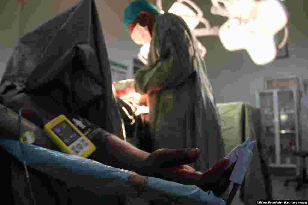 Female patient monitored using Lifebox pulse oximeter [essential oxygen monitor] during emergency Caesarean section.