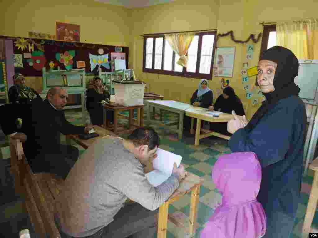 A polling station worker checks for voters names on the list in a polling station in Cairo, Egypt, Dec. 1, 2015. (Photo - H. Elrasam/VOA)