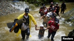 Un grupo de migrantes de Venezuela, Ecuador y Haití cruzan el río Muerto en el Tapón de Darién, mientras continúan su viaje hacia la frontera de EEUU, en Acandi, Colombia, el 9 de julio de 2023.