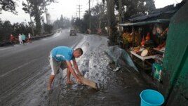 Residents cleans ash fall from Taal Volcano's eruption Monday Jan. 13, 2020, in Tagaytay, Cavite province, south of Manila, Philippines. (AP Photo/Aaron Favila)