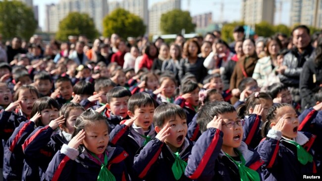 2018年2月23日，中国上海一所小学新学期第一天举行的升旗仪式上，学生们致敬。