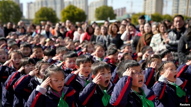 2018年2月23日,中国上海一所小学新学期第一天举行的升旗仪式上,学生们致敬。