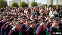 资料照：中国上海一所小学的学生们在新学期第一天举行的升旗仪式上敬礼。(2018年2月23日)