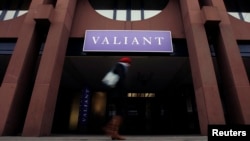 FILE - A woman walks past a building of the Swiss bank Valiant in Lucerne.