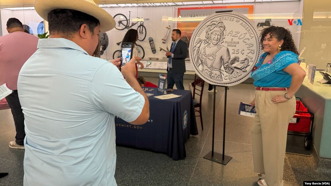 Una mujer posa junto a una réplica de la moneda de 25 ctvs de dólar que lleva la imagen de la cantante Celia Cruz, durante una noche de celebración a la "Reina de la Salsa", en el Museo Nacional de Historia Estadounidense, el 20 de septiembre de 2024 en Washington. 