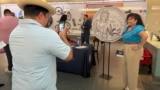 Una mujer posa junto a una réplica de la moneda de 25 ctvs de dólar que lleva la imagen de la cantante Celia Cruz, durante una noche de celebración a la "Reina de la Salsa", en el Museo Nacional de Historia Estadounidense, el 20 de septiembre de 2024 en Washington. 