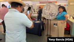 Una mujer posa junto a una réplica de la moneda de 25 ctvs de dólar que lleva la imagen de la cantante Celia Cruz, durante una noche de celebración a la "Reina de la Salsa", en el Museo Nacional de Historia Estadounidense, el 20 de septiembre de 2024 en Washington. 