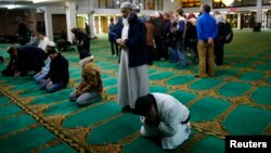 FILE - Men pray as visitors are given a tour of the Birmingham Central Mosque, on visit my mosque day in Birmingham, Feb. 7, 2016. 