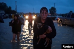 A woman holds her dog as she arrives to high ground after evacuating her home due to floods caused by Tropical Storm Harvey along Tidwell Road in east Houston, Texas, U.S. August 28, 2017.
