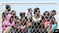 FILE - Migrants wait to disembark from the Italian Navy vessel 'Bettica' in the harbor of Salerno, Italy, May 5, 2015.