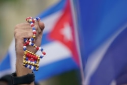 A demonstrator holds up a bead necklace in the colors of the Cuban flag, July 14, 2021, in Miami's Little Havana neighborhood, as people rallied in support of antigovernment demonstrations in Cuba.