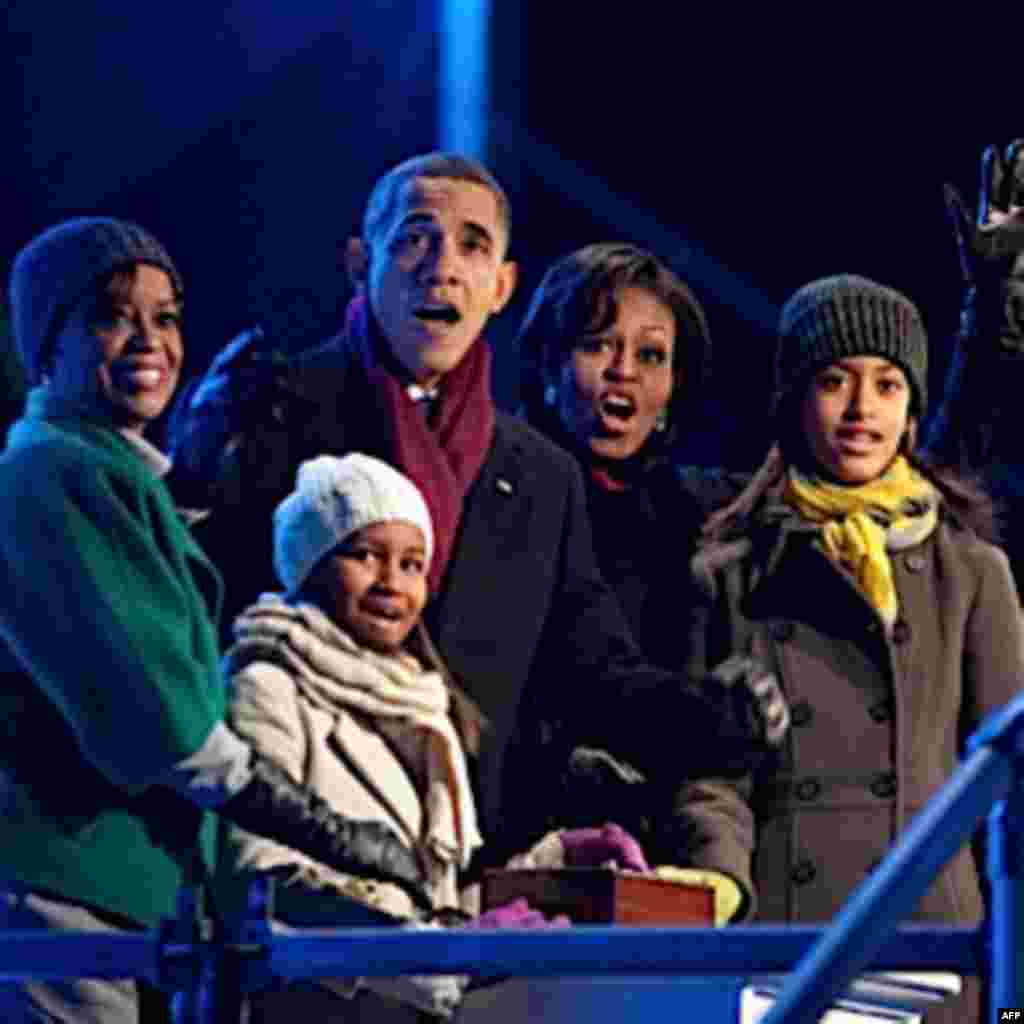 President Barack Obama, with mother-in-law Marian Robinson, daughters Sasha and Malia, and First Lady Michelle Obama, react as they push the button to light the National Christmas Tree during a ceremony on the Ellipse in Washington, D.C., Dec. 9, 2010. (O