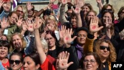 Turkish women with red points painted on their hands gather outside the Turkish parliament to protest a draft law granting muftis the right to register marriage contracts, in Ankara, Oct. 12, 2017.