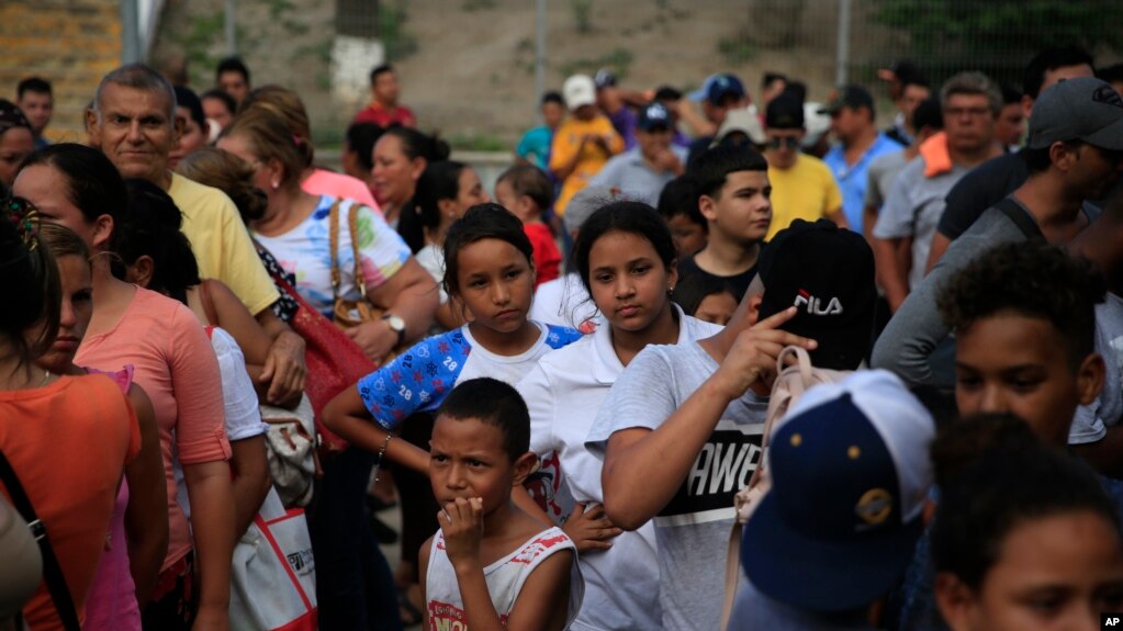 Migrantes de varios países latinoamericanos hacen fila para recibir alimentos de voluntarios estadounidenses al pie del puente que cruza a Brownsville, Texas, en Matamoros, México. Cientos esperan por meses en fila para solicitar asilo en EE.UU. Foto de junio 26 de 2019.