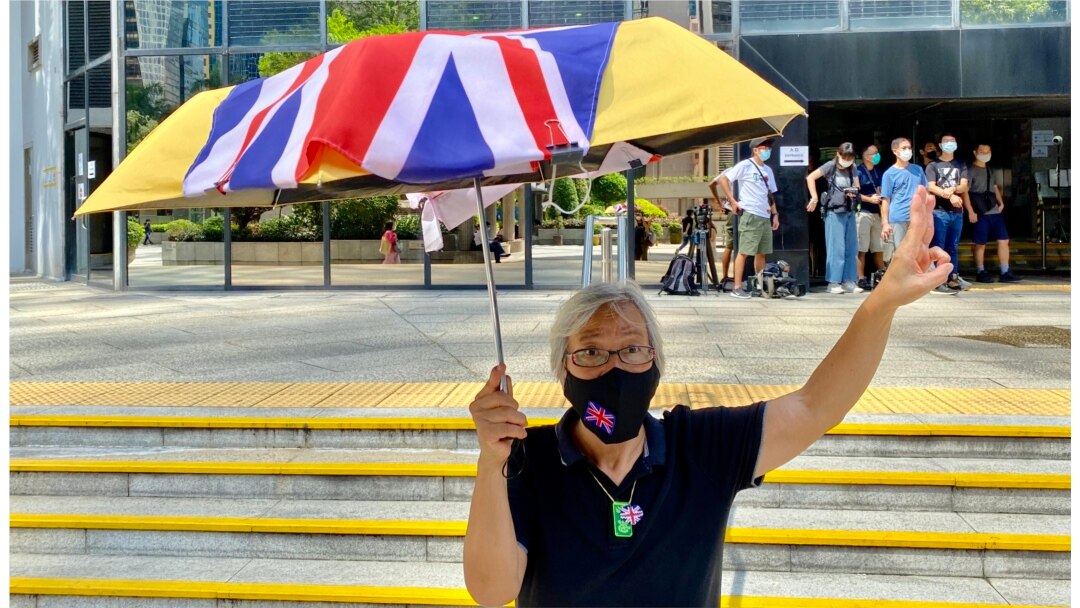 社运人士王婆婆9月15日在湾仔区域法院外撑起贴上英国国旗的黄伞,声援六四未经批准集结案,12名认罪的被告(美国之音/汤惠芸)