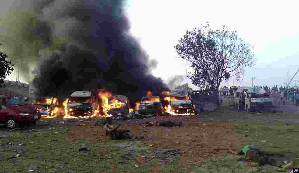 Vítimas da explosão caídas no chão num cenário de chamas e fumo numa estação de autocarros, Abuja, Abril 14, 2014.