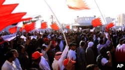 Bahraini anti-government protesters wave national flags and signs calling for regime change, March 2, 2011, outside the main police headquarters in the capital of Manama