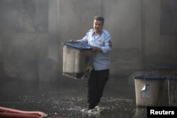 FILE - An official carries a ballot box after a fire at a storage site in Baghdad that houses the boxes from Iraq's May parliamentary election, Iraq, June 10, 2018.